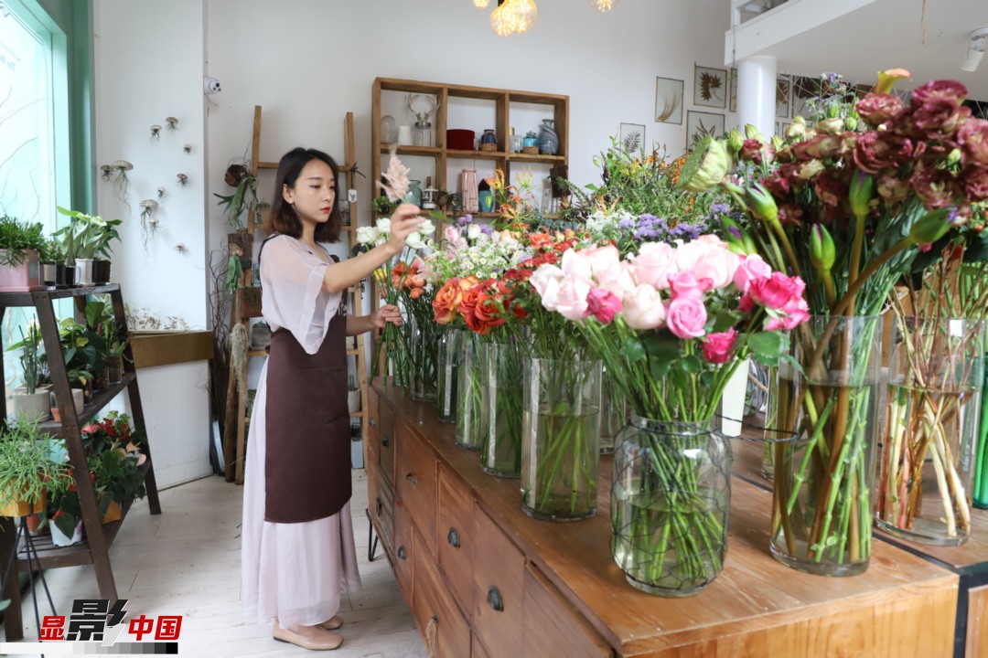 王黎媛是一名河南姑娘，在昆明念完大學后，就再也舍不下春城的藍天陽光、青山碧水，更舍不下這里的四時繁花，于是就干脆留了下來，成了一名媒體人。2017年的時候又毅然辭去工作，創業開起了花店，成了都市里的一名“花房姑娘”。圖為王黎媛在自己的花店中整理鮮花。新華網 周亞平/攝 念新洪/文
